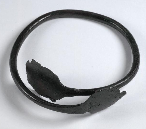 A photograph of round copper shaped like a headband with widened terminals